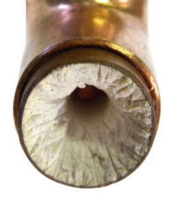 Close-up of pipe clogged with hard water scale, showing buildup ScaleBlaster helps prevent. 