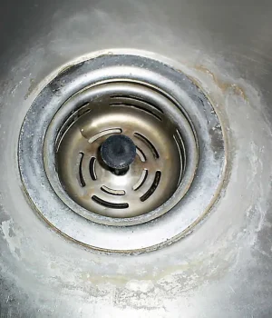 Sink drain with heavy limescale buildup, showing hard water issues ScaleBlaster helps eliminate.
