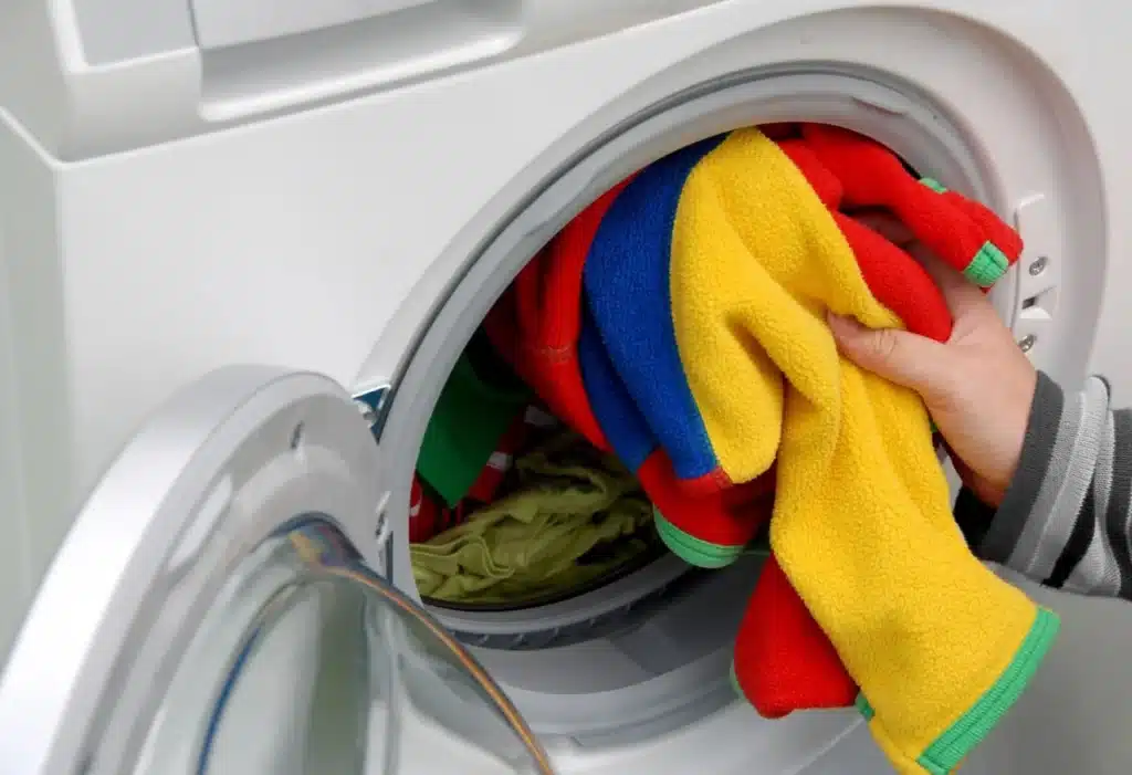 Bright laundry being removed from washer, showing cleaner clothes with ScaleBlaster-treated water.